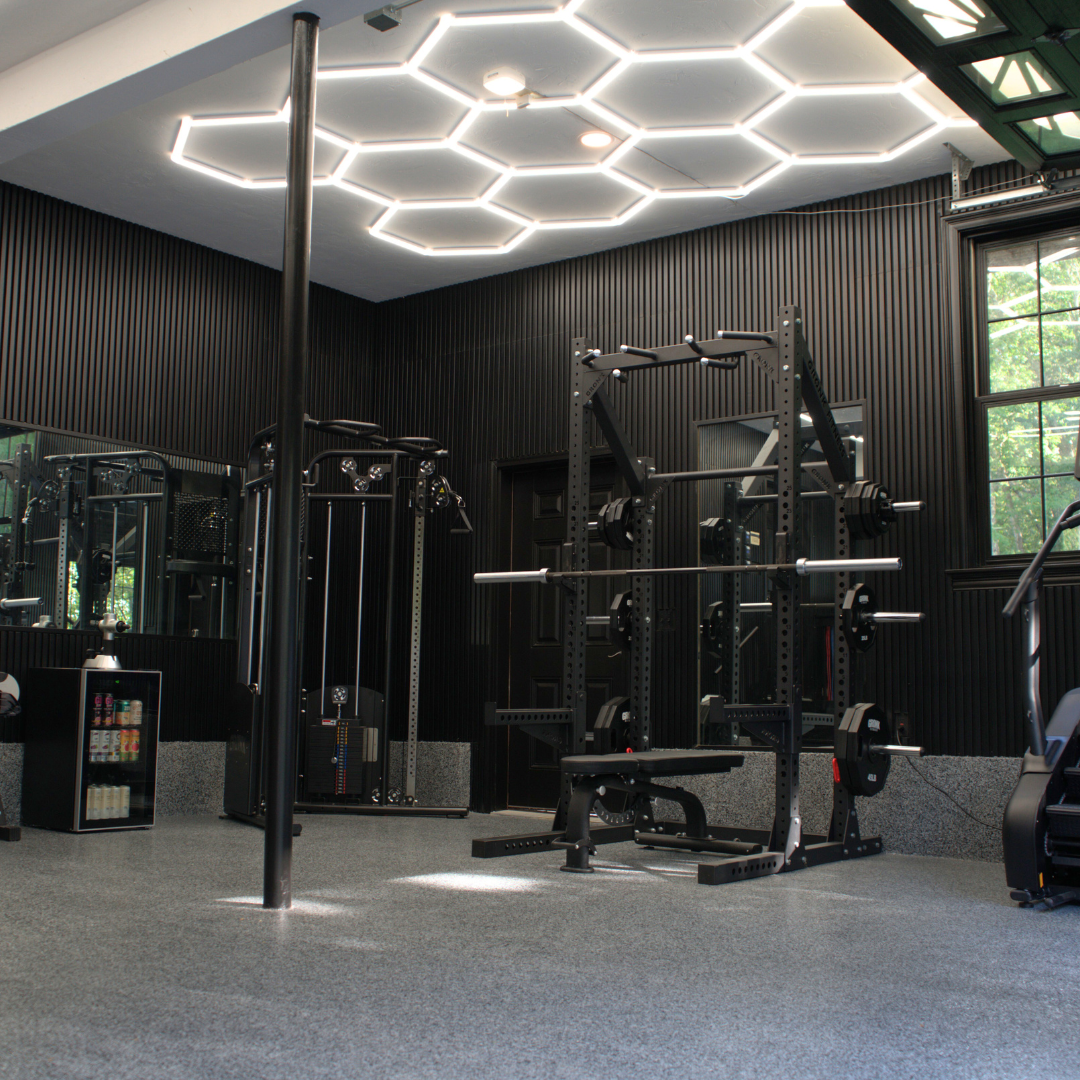 Home garage gym setup featuring the Gronk Fitness XFT Functional Trainer V2, a set of Gronk Fitness Competition and Premium Bumper Plates, and the Gronk Fitness Squat Stand with J Hooks, showcasing high-quality strength training equipment by G&G Fitness.
